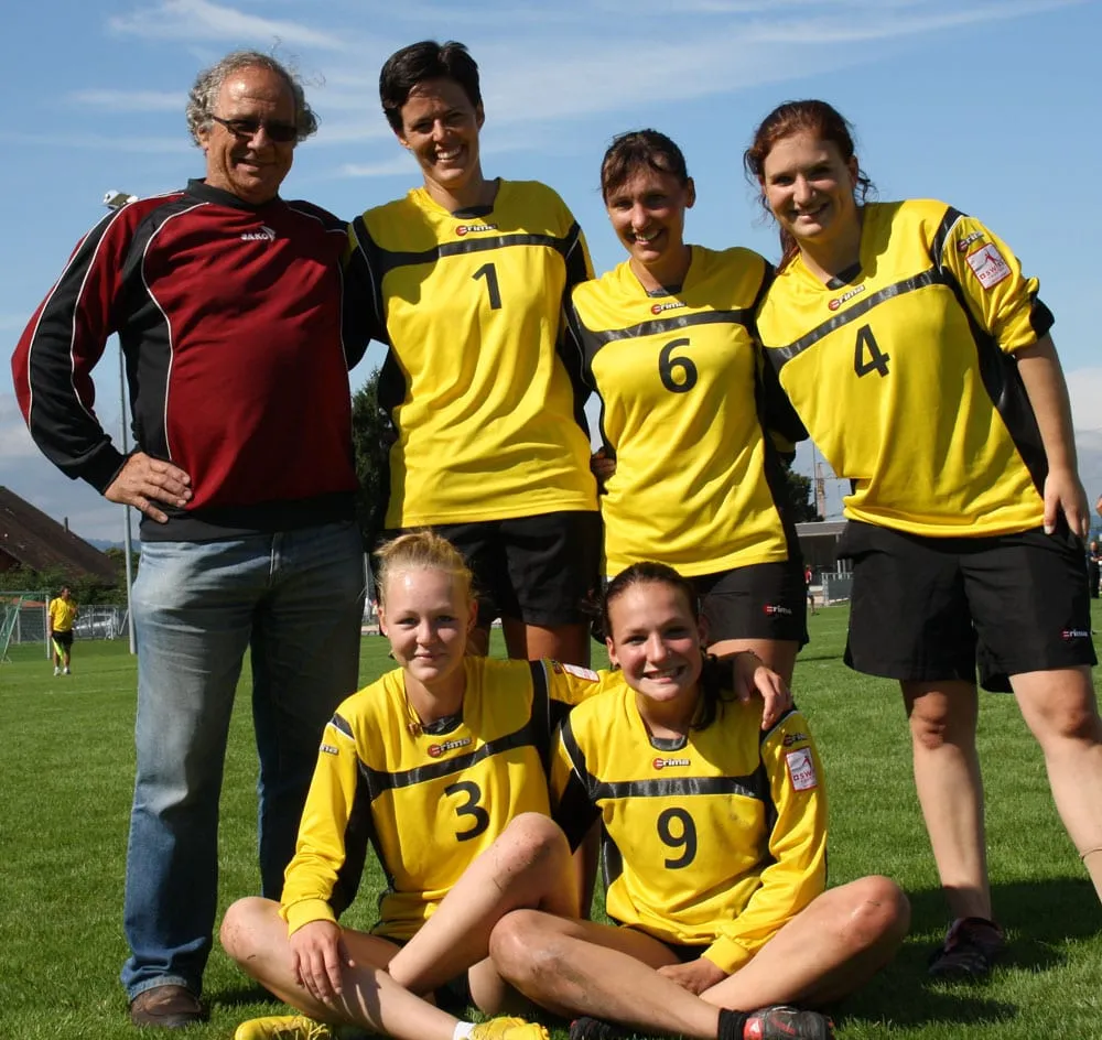 Die Faustball-Frauen in gelben Trikots mit ihrem Trainer