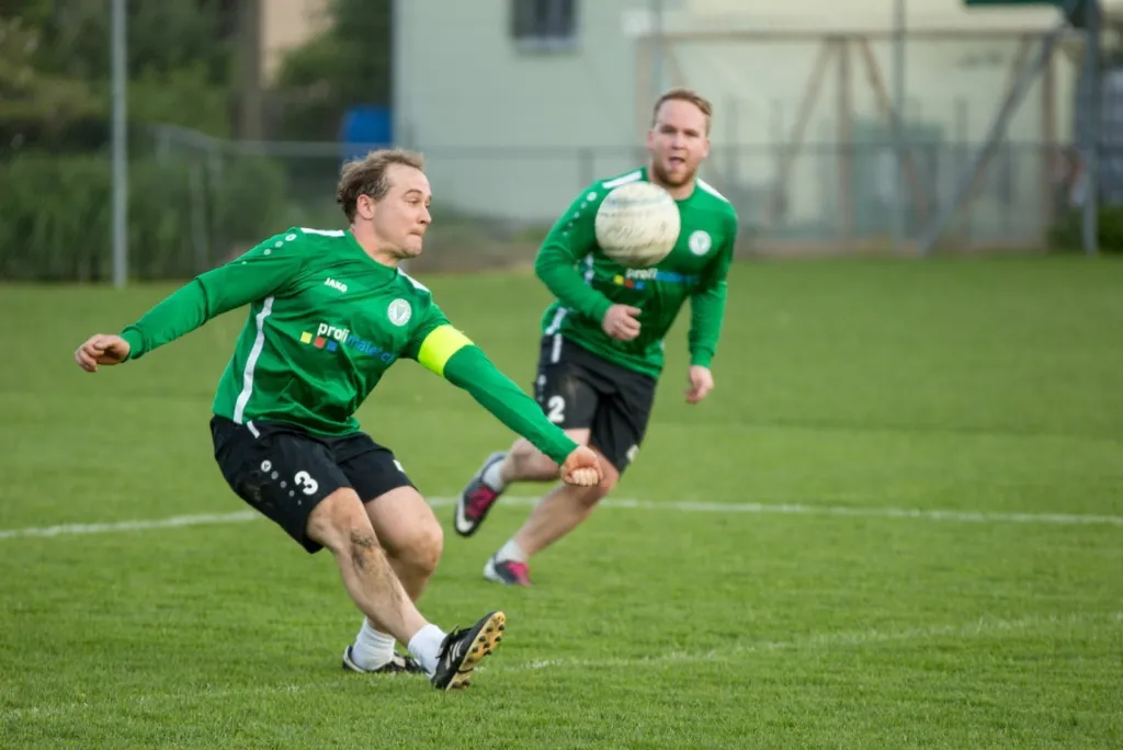 Faustball-Spielszene mit zwei Spielern in grünen Trikots
