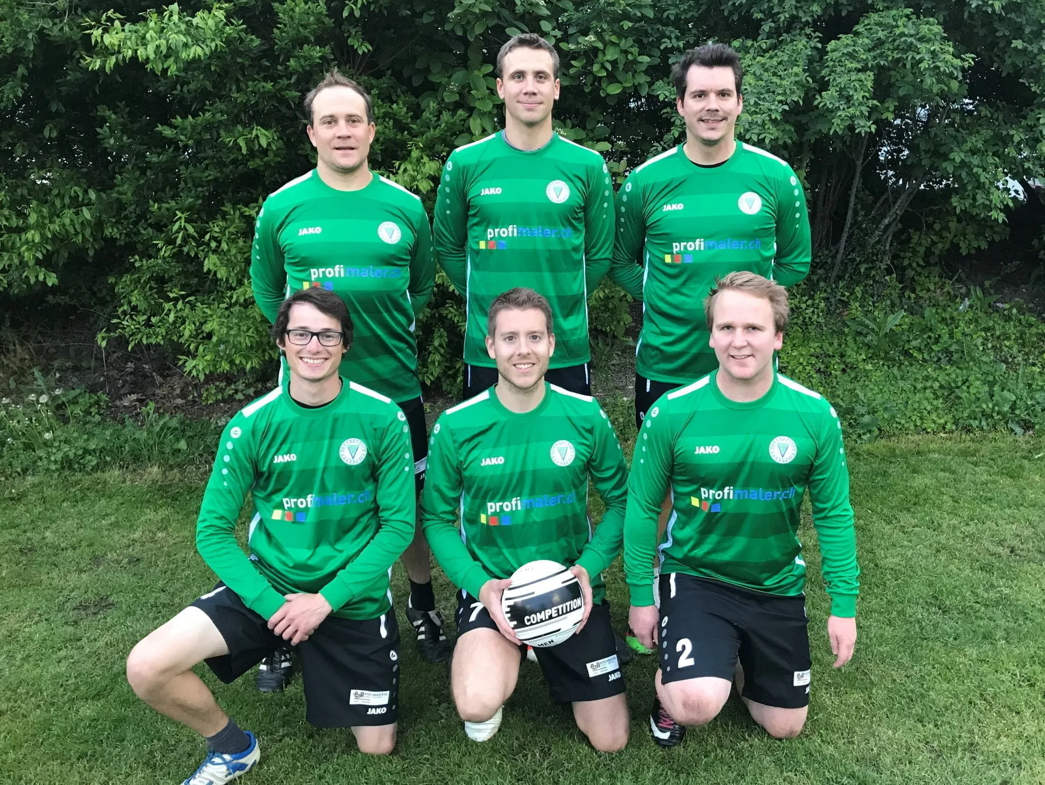 Faustball-Mannschaft in grünen Trikots vor einer Hecke