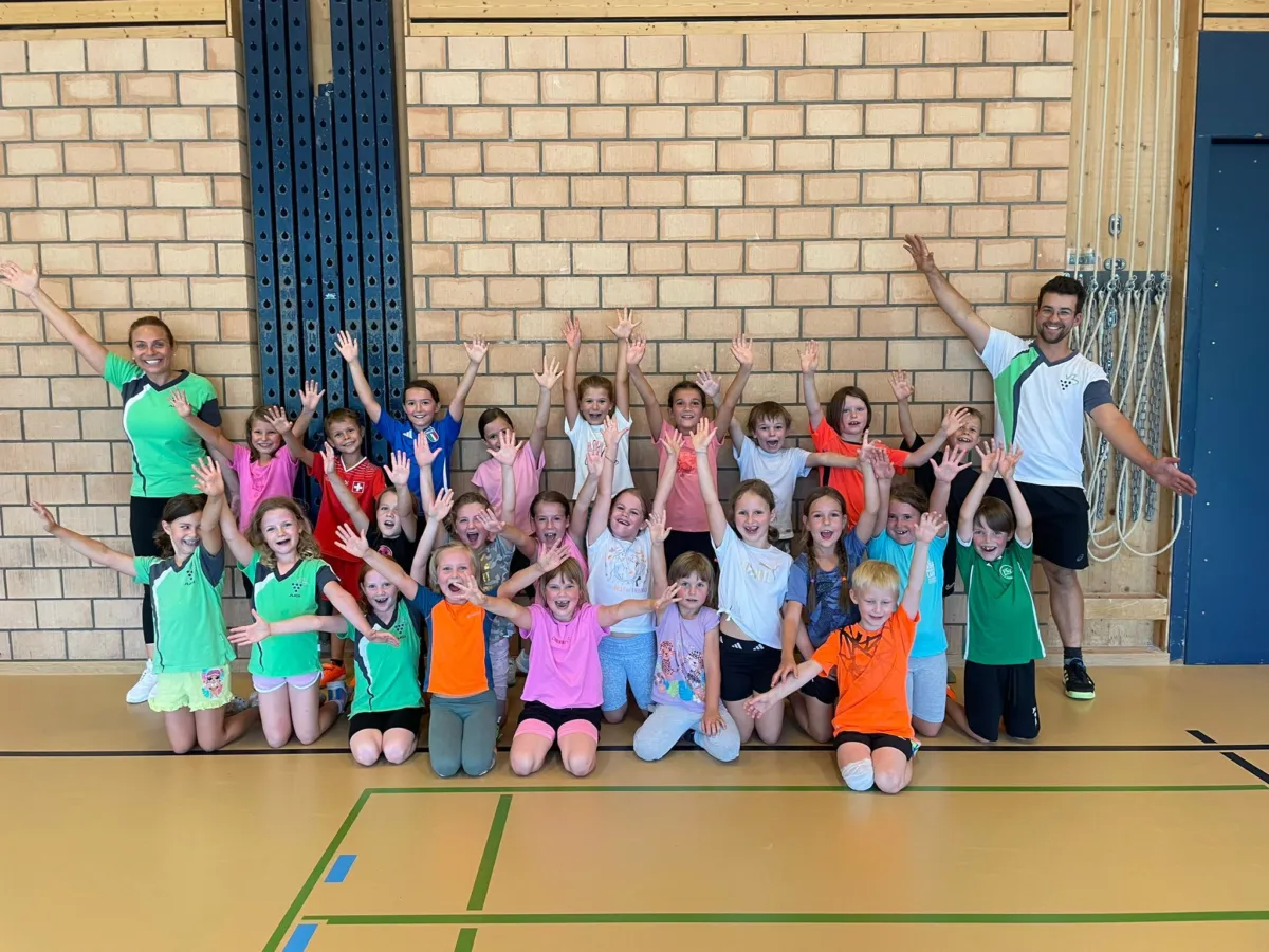 Kinderturnen: Mädchen und Knaben mit erhobenen Armen in der Turnhalle