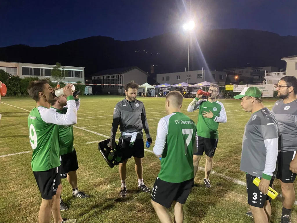 Faustballer im Gespräch auf dem Spielfeld unter Flutlicht