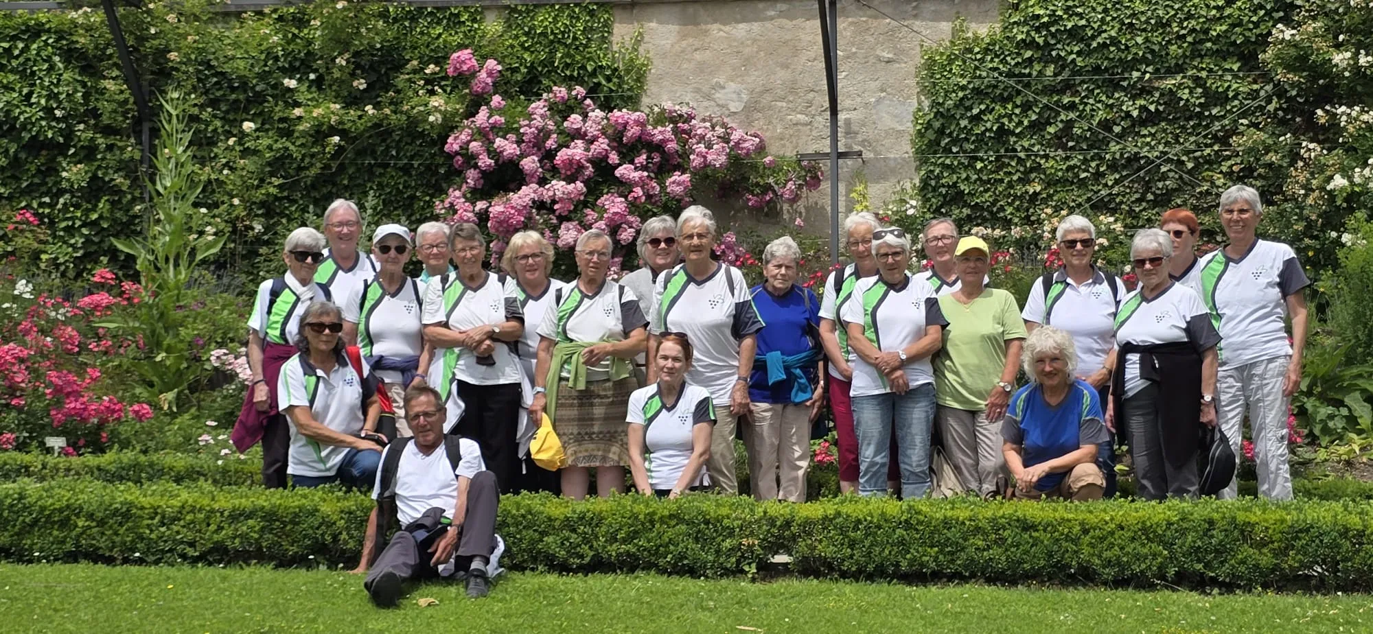 Die 60+ Riege beim Ausflug in einem Garten mit blühenden Sträuchern