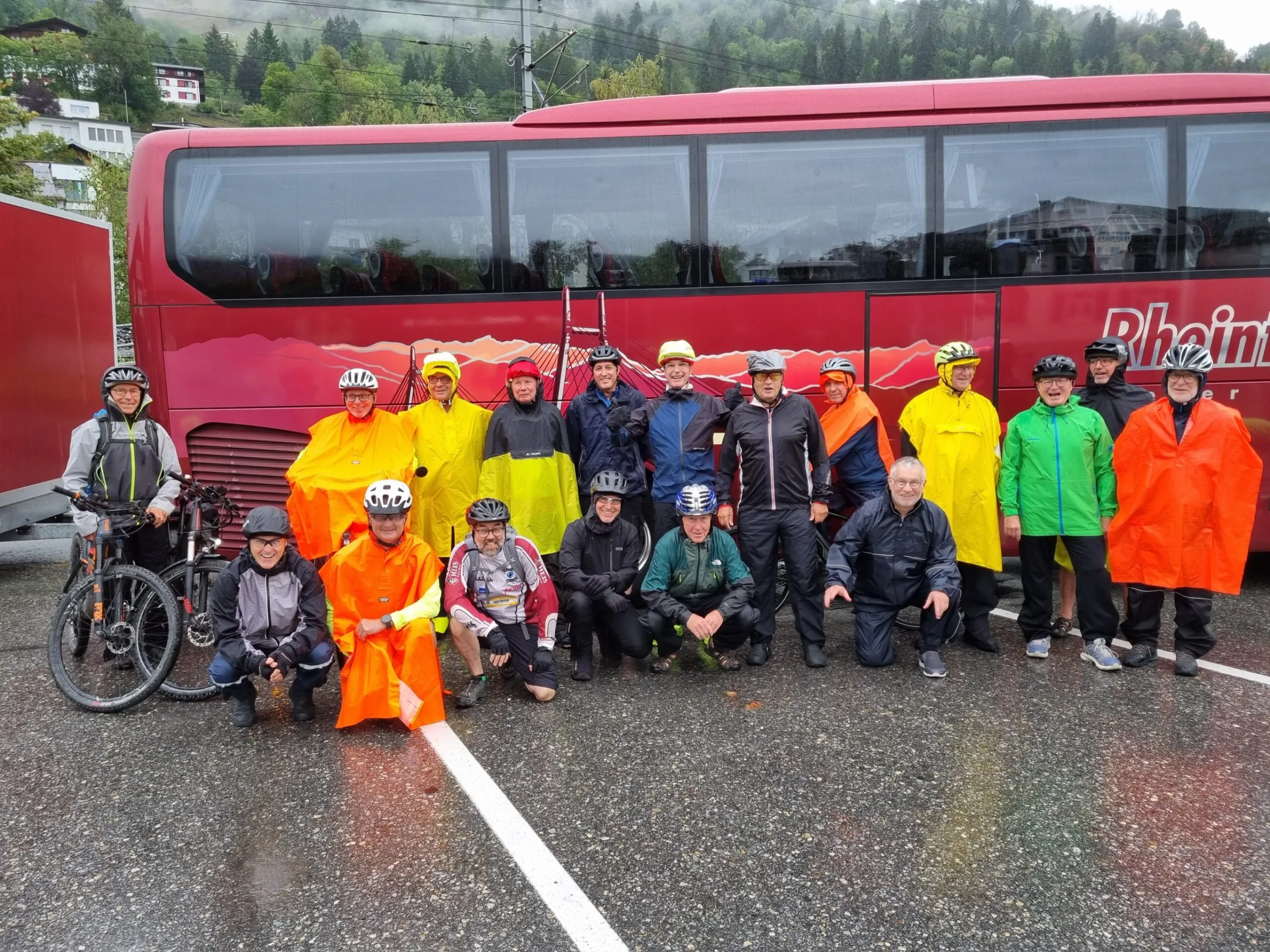 Gruppenbild der Männerriege in Regenkleidung mit Velos vor einem Reisecar